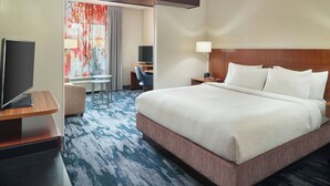 Ein Hotelzimmer mit einem großen Bett, einem Schreibtisch, einem Fernseher und einem Sessel.