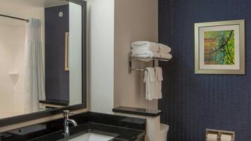 A bathroom with a black countertop sink, a mirror, a towel rack, and a framed picture on the wall.