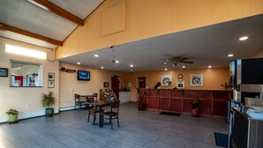 A spacious indoor area with a wooden ceiling, a dining table with chairs, a kitchen area with a counter, and several potted plants. - Mahoning Inn (Lehighton)