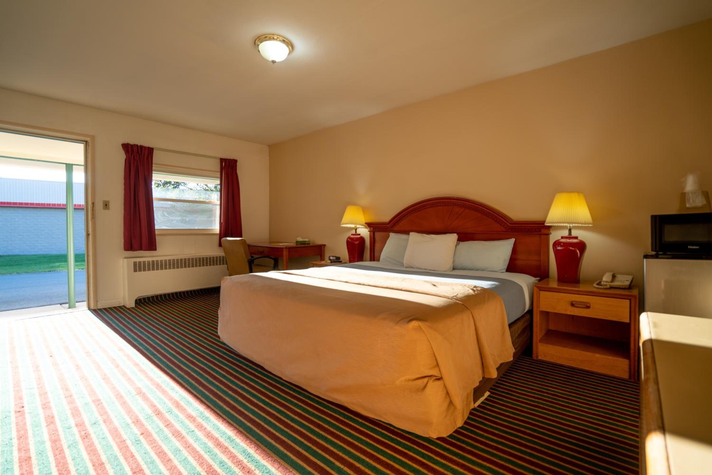 Habitación de hotel con una cama grande, dos lámparas de noche, un escritorio y vistas al mar.