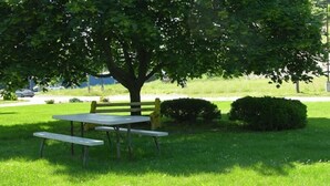 A picnic table and bench under a tree in a grassy area. - Mahoning Inn (Lehighton)