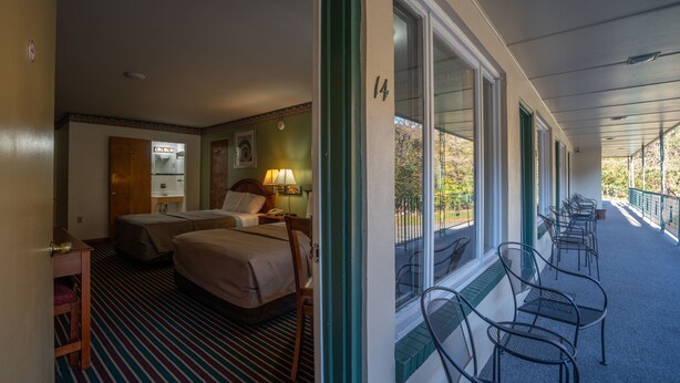 A hotel room with two beds, a bathroom, and a balcony with chairs. - Mahoning Inn (Lehighton)