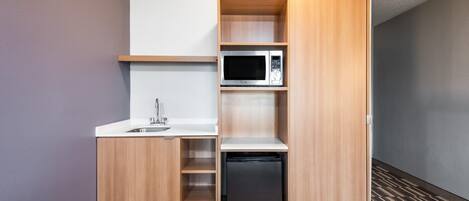 Une petite cuisine équipée d’un four à micro-ondes, d’un évier et d’un réfrigérateur encastré.