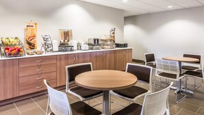 A breakfast area with a counter, seating, and a fruit display.