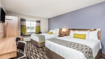 A hotel room with two beds, a desk, and a TV.