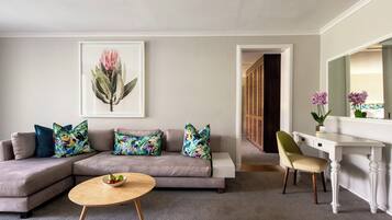 A living room with a sectional sofa, a round coffee table, a white desk, and a large mirror.