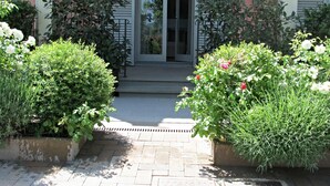 A building entrance with a glass door, surrounded by well-maintained bushes and flowers.