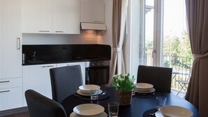 A modern kitchen with white cabinets, a black countertop, and a dining area with a table set for four.
