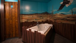 A bathroom with a large bathtub, wooden walls, and a mural of a desert landscape. - Western City (Chaudfontaine)