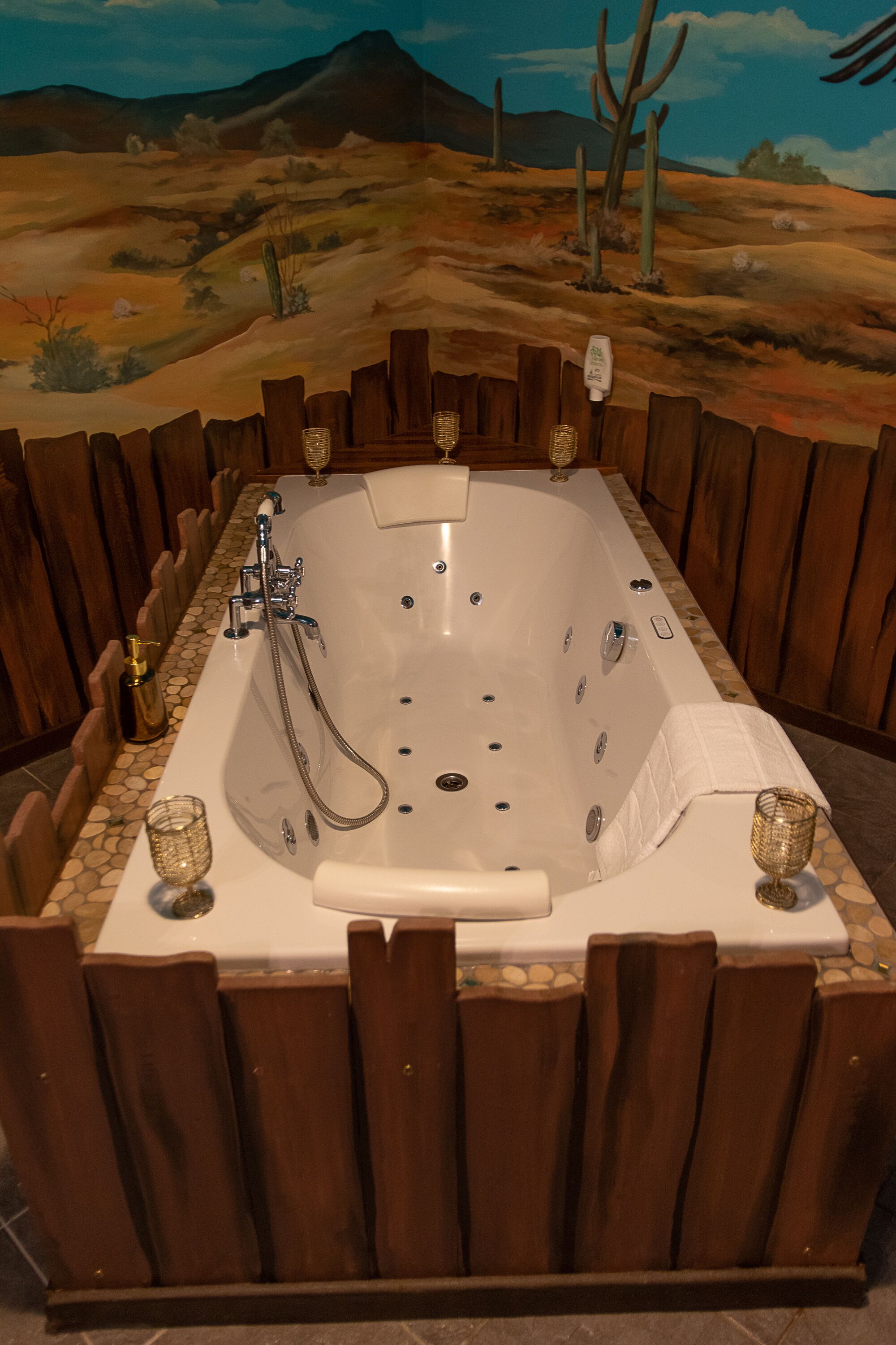 A large, rectangular bathtub with multiple faucets and a showerhead, surrounded by wooden panels and stone tiles.