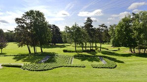 A well-maintained golf course with manicured lawns, trees, and a clear sky. - Western City (Chaudfontaine)