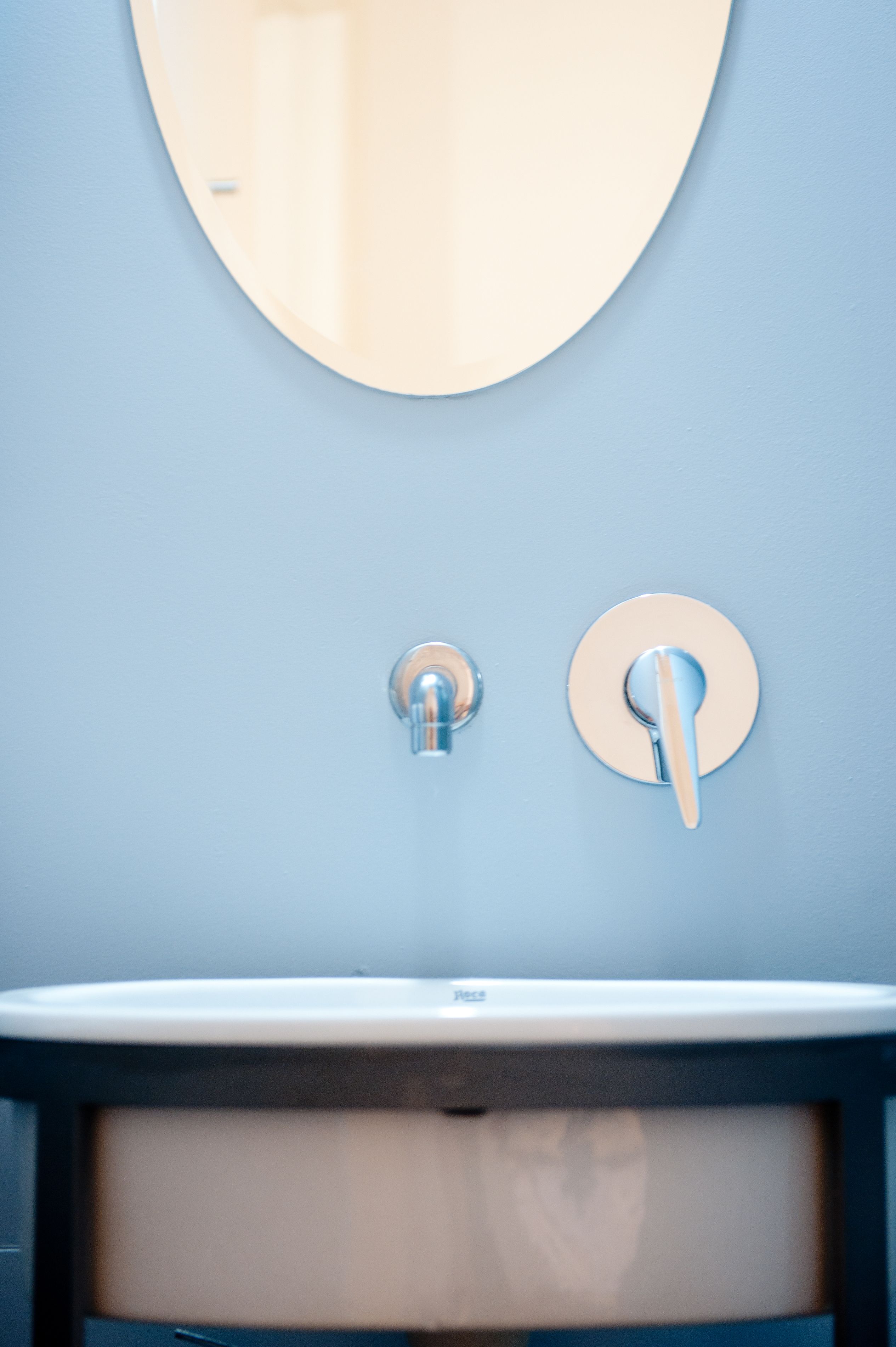 A bathroom with a round mirror, a sink, and a faucet.