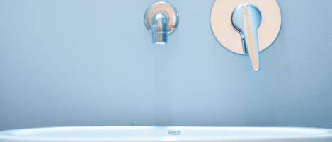 A bathroom with a round mirror, a sink, and a faucet.