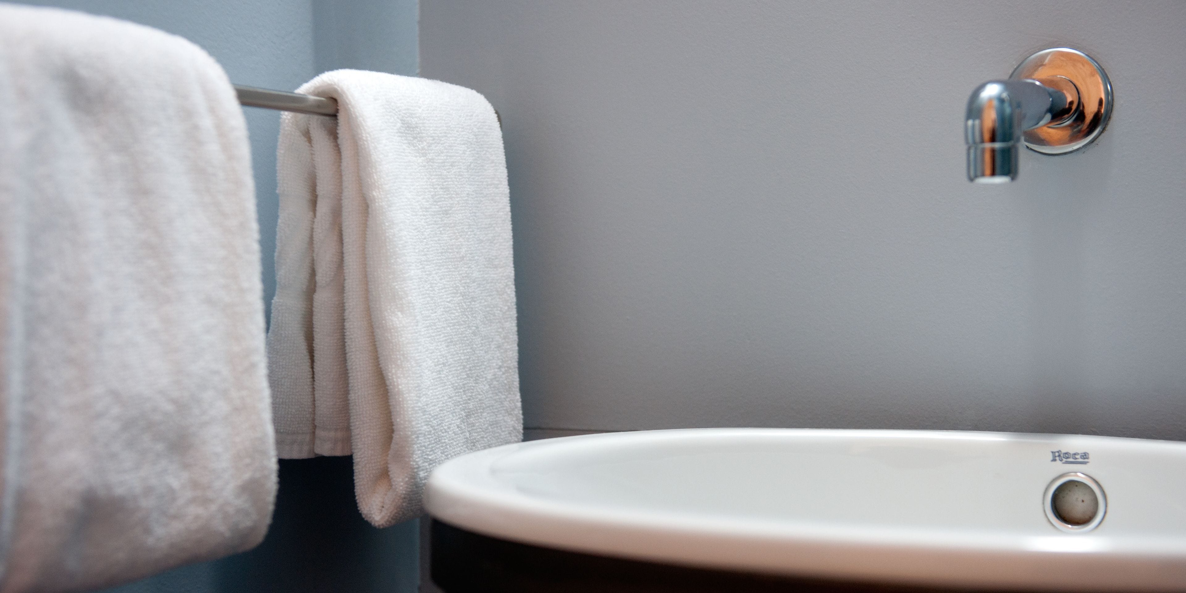 A bathroom with a white sink and a towel rack with two towels.