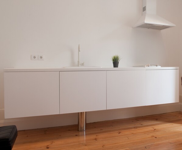 A modern kitchen with white cabinets, a stainless steel sink, and a small potted plant on the countertop. - Miguel Torga Vintage Lofts (Coimbra)