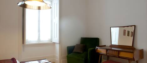 A room with a wooden desk, a green chair, a red bench, and a hanging lamp.