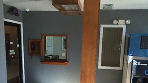 A hotel lobby with a large wooden pillar, a reception desk, a vending machine, and a door to the hotel office. - Wilshire Inn (Cushing)