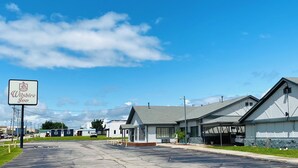 A parking lot with a Wilshire Inn sign, a building with a covered porch, and a garage. - Wilshire Inn (Cushing)