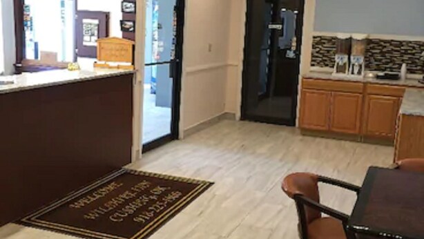 A kitchen with a wooden countertop, a refrigerator, and a dining area with a table and chairs. - Wilshire Inn (Cushing)