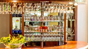 A bar area with shelves of glassware and a bowl of green leaves on the counter. - Les chambres d'hotes de la Villa Cayol (Fort-de-France)