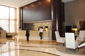 A lobby with a reception desk, seating area, and a large pillar.