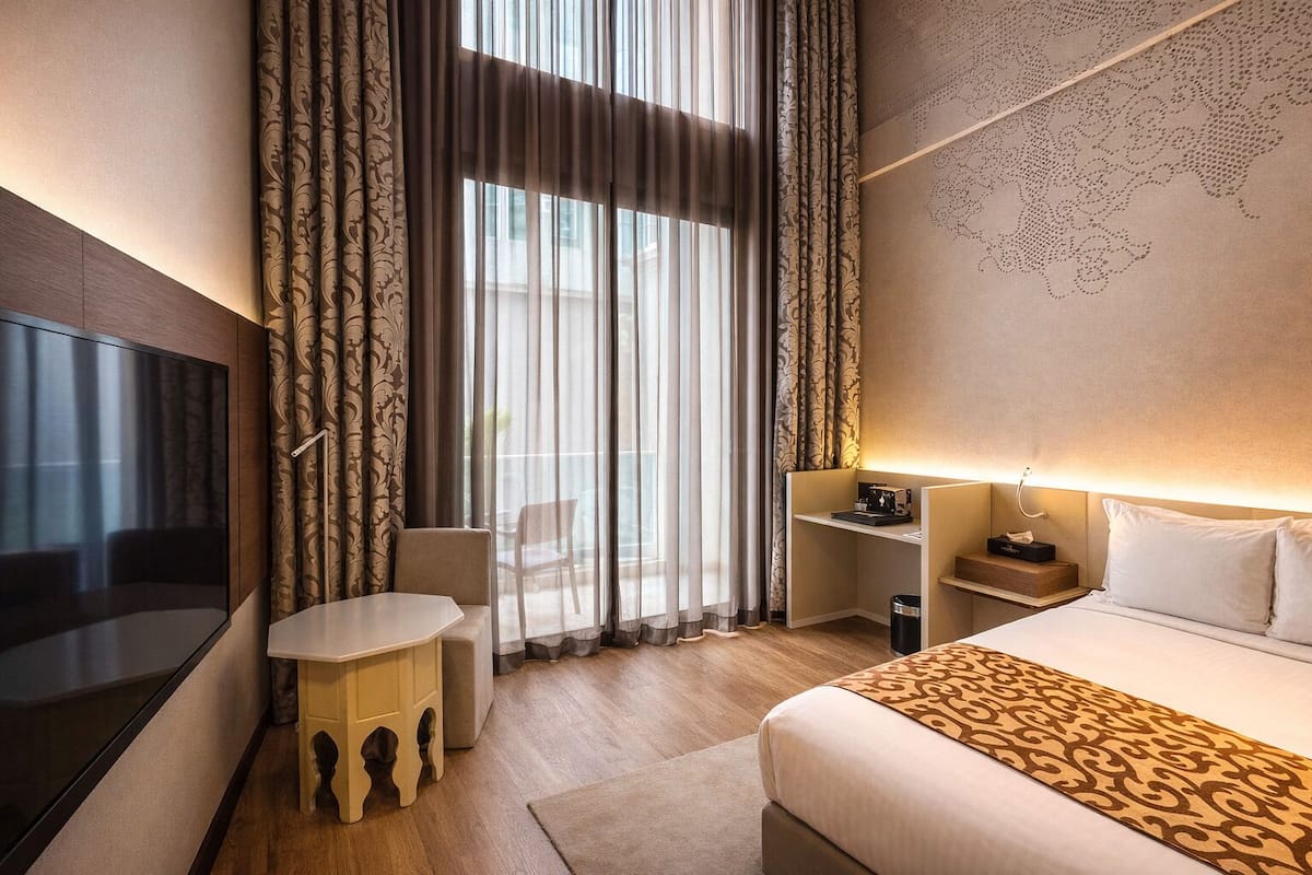 Une chambre d’hôtel avec un lit, un bureau, une chaise et un téléviseur.