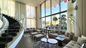 Een moderne woonkamer met een gebogen trap, grote ramen en eigentijds meubilair.
