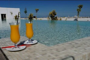 Una piscina al aire libre, sombrillas, sillones reclinables de piscina
