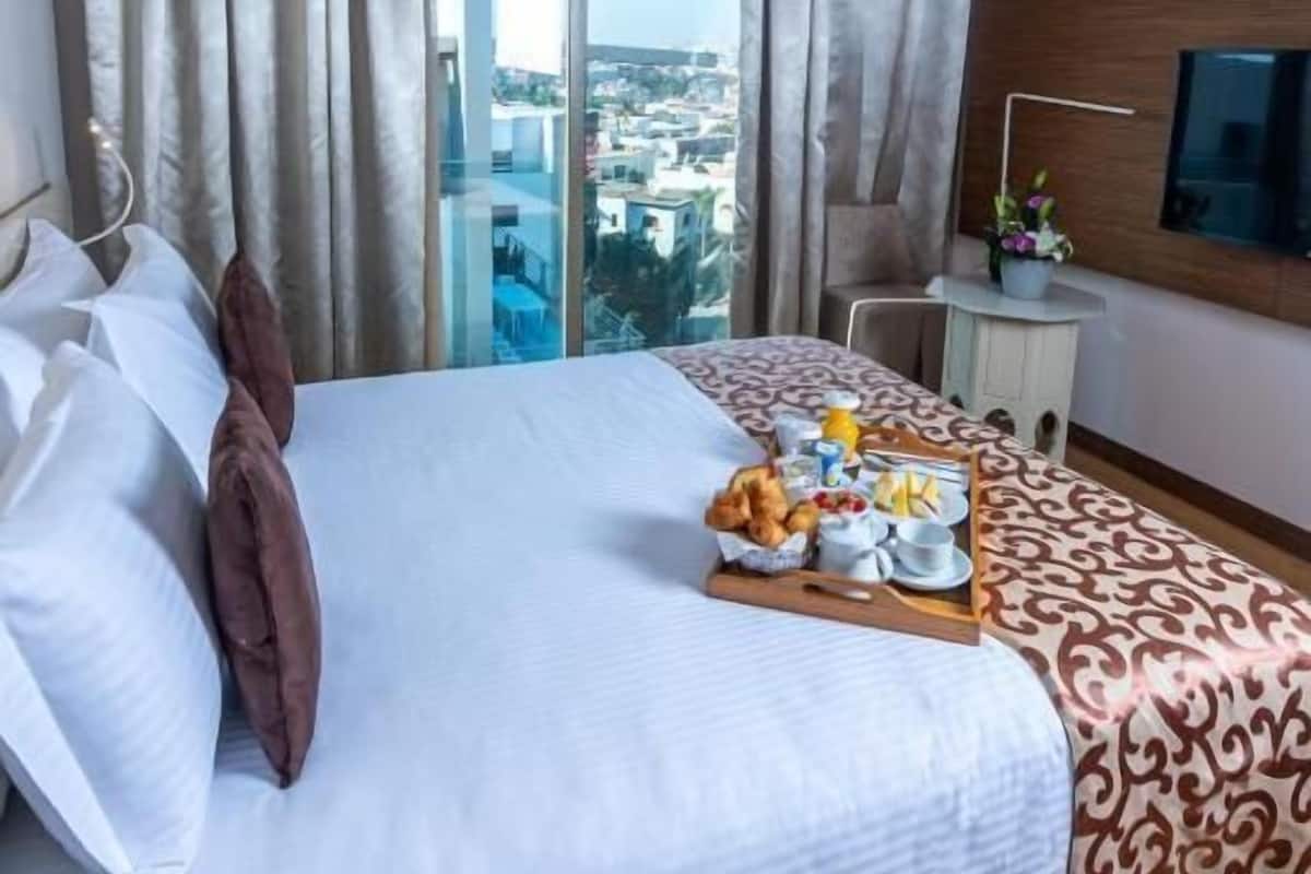 Une chambre d’hôtel avec un grand lit, un bureau, une télévision et une vue sur la ville.