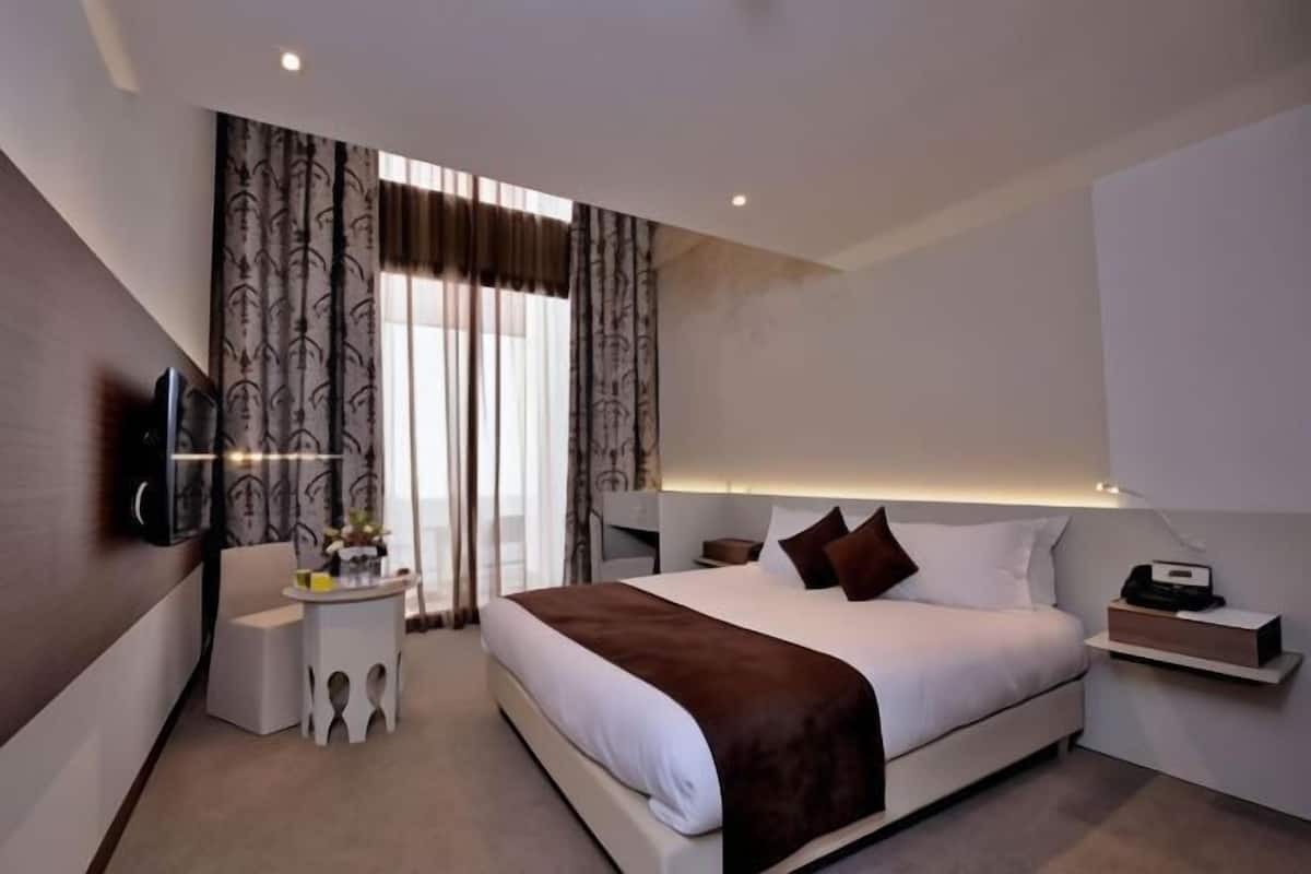 Une chambre d’hôtel moderne, dotée d’un grand lit, de tables de chevet, d’une télévision et d’un bureau.
