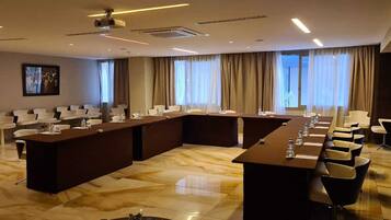 A conference room with a long table, multiple chairs, and a projector screen.
