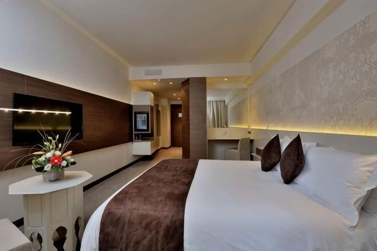 Une chambre d’hôtel moderne dotée d’un grand lit, d’un téléviseur à écran plat, d’un bureau et d’un vase décoratif.