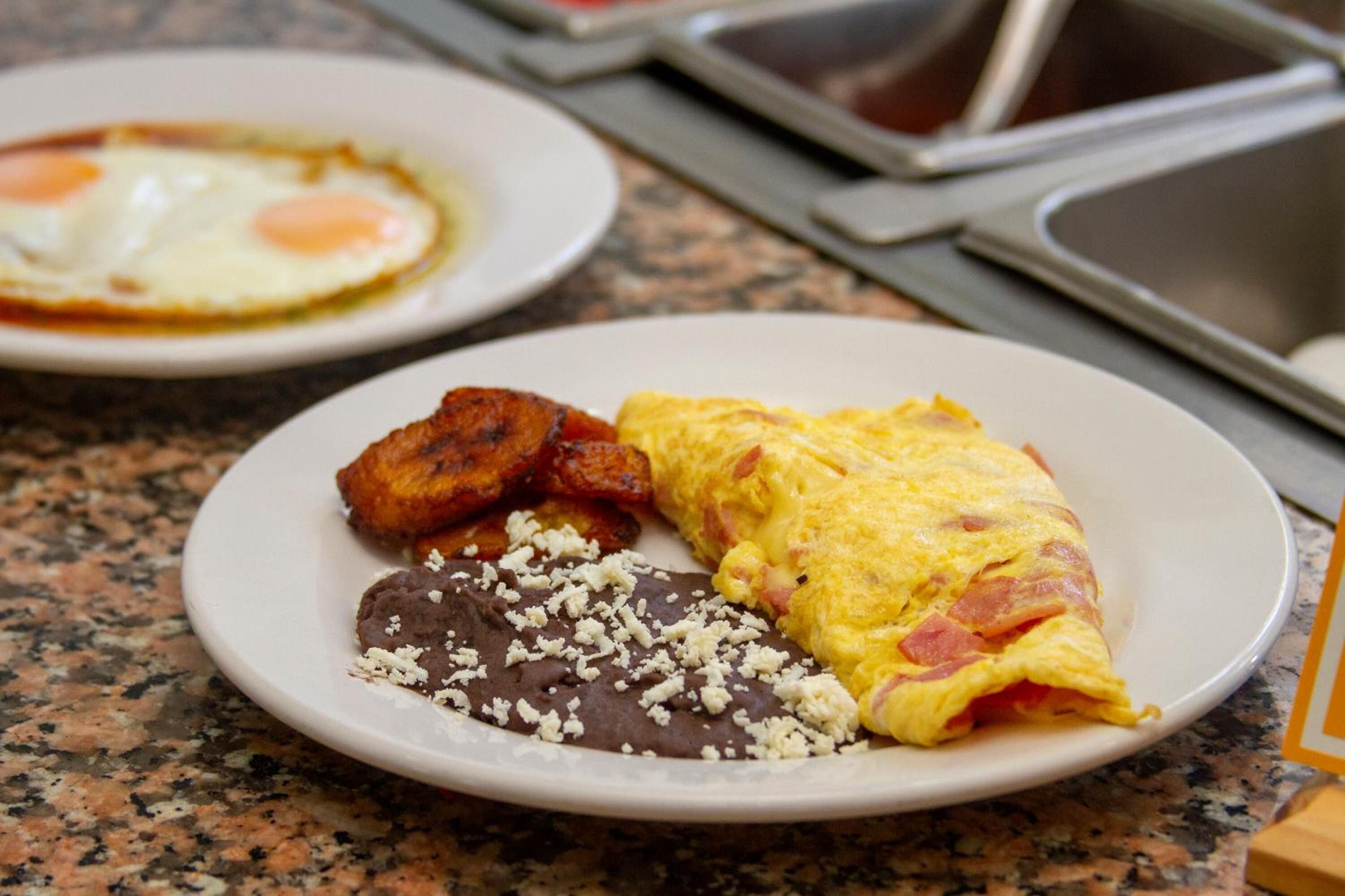 A plate with an omelet, beans, and fried plantains.
