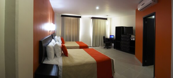 A hotel room with two beds, a desk with a computer, a TV, and a minibar. - Hotel Baez Paraiso (Paraiso)