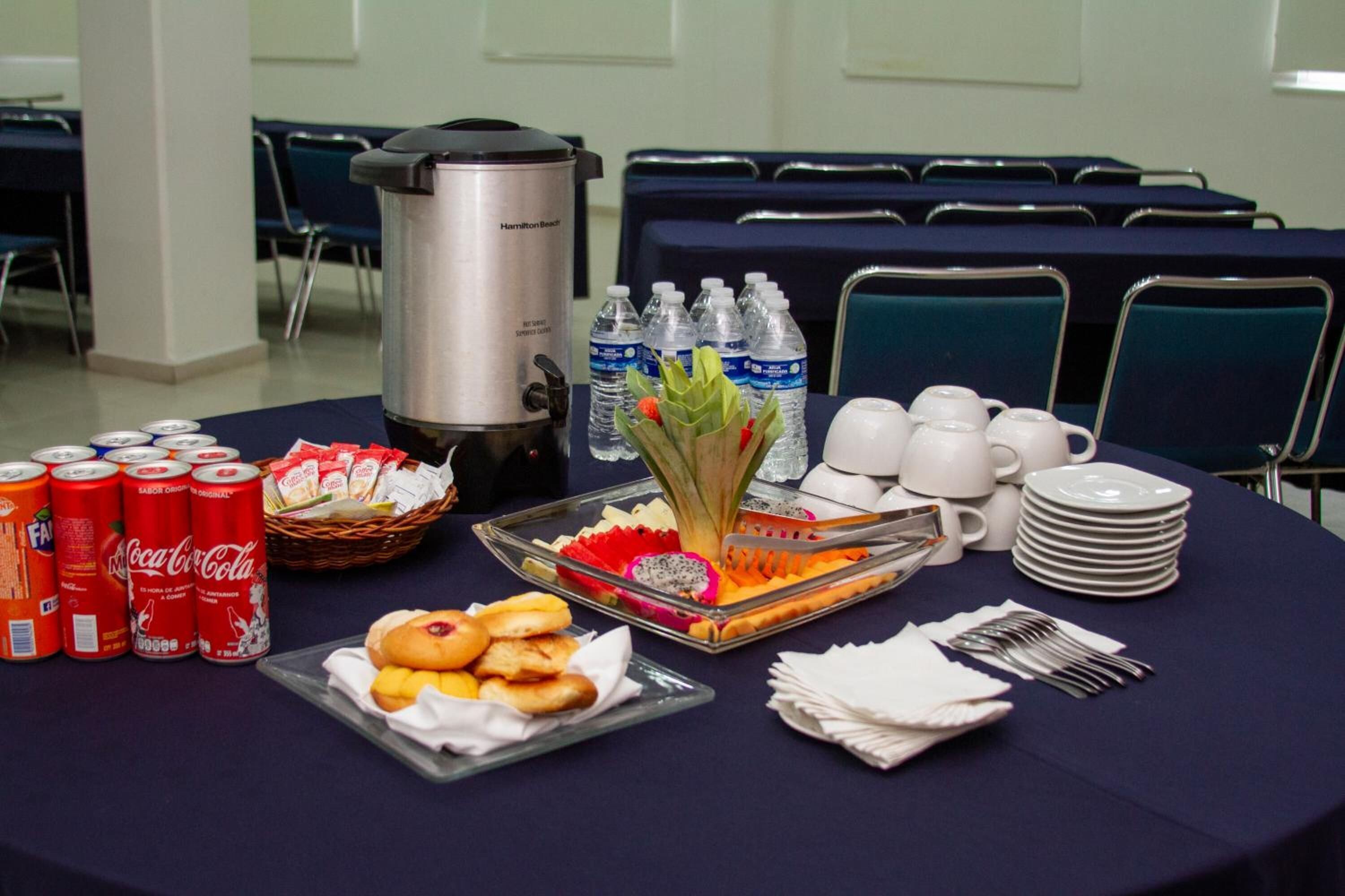 A breakfast buffet table with beverages, snacks, and a coffee maker.