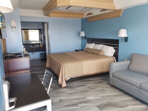 Una habitación de hotel con cama, sofá, escritorio y espejo.