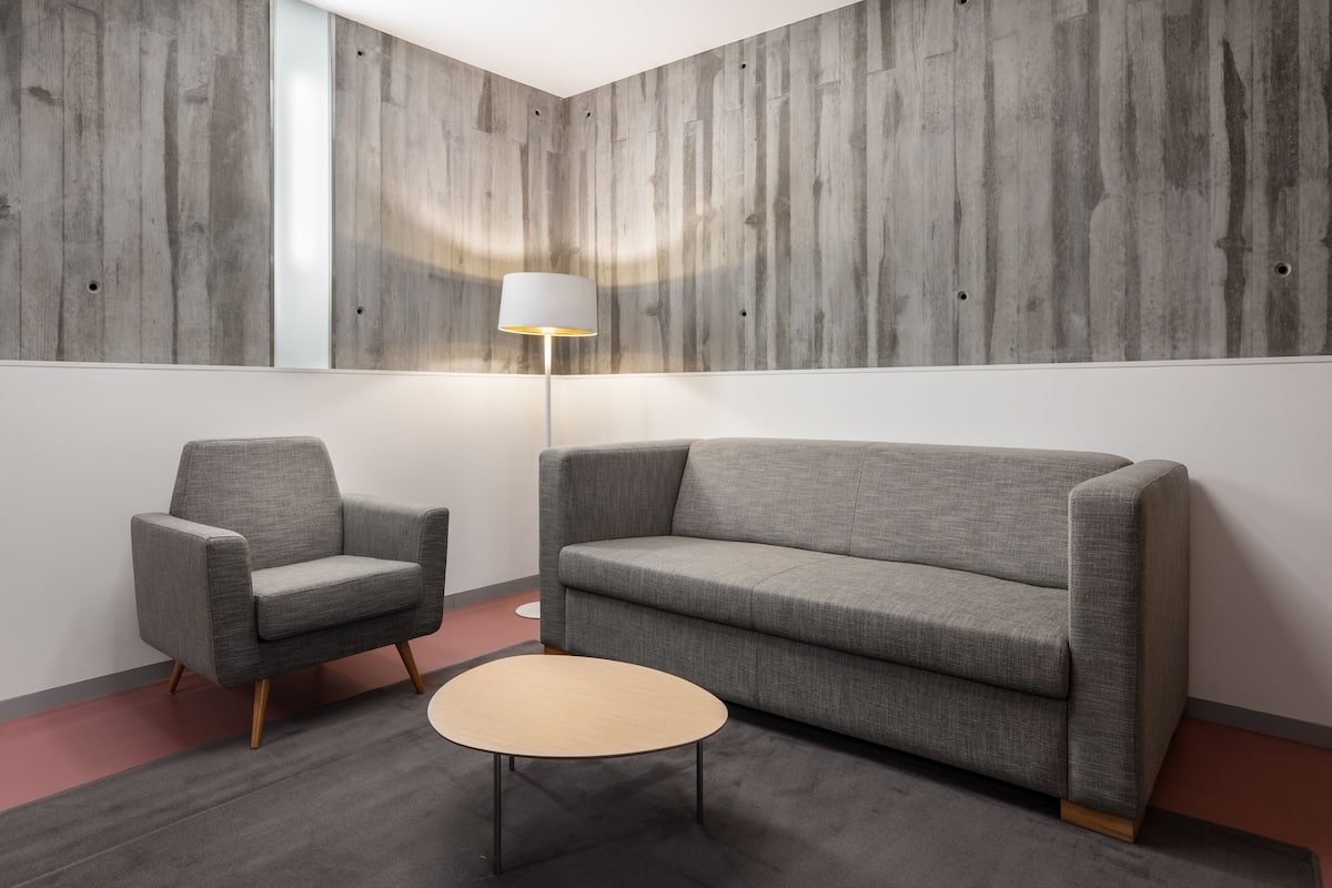 A modern room with a grey sofa, a grey armchair, and a small round table.