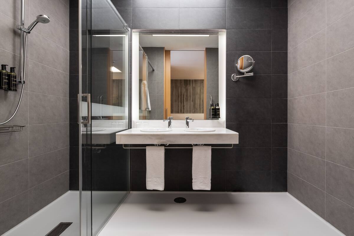 A modern bathroom with a glass-enclosed shower, a double sink vanity, and a large mirror.