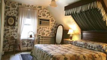 A bedroom with a bed, a chair, a window with curtains, a radiator, and a lamp.
