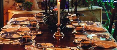 Uma mesa de jantar posta com pratos, tigelas e uma vela acesa.