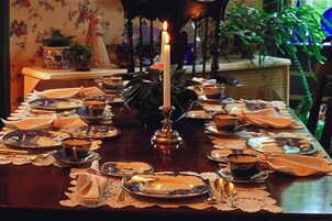 Una mesa de comedor con platos, tazones y una vela encendida.