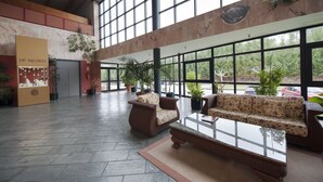Un hall d’entrée spacieux, doté de grandes fenêtres, d’un comptoir d’accueil et de coins salons confortables.