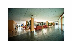 Un hall d’entrée spacieux, doté d’un sol carrelé, de coins salon et de grandes fenêtres laissant entrer la lumière naturelle.