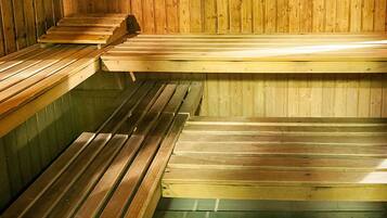 Una sauna con bancos de madera y una cuchara de madera sobre uno de los bancos.