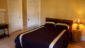 Un dormitorio con una cama grande, dos puertas, una mesita de noche y una lámpara.