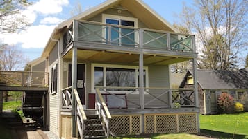 Une maison à deux étages avec un balcon, une véranda et un petit jardin.