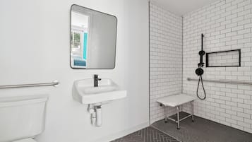 A modern bathroom with a white sink, mirror, and toilet.