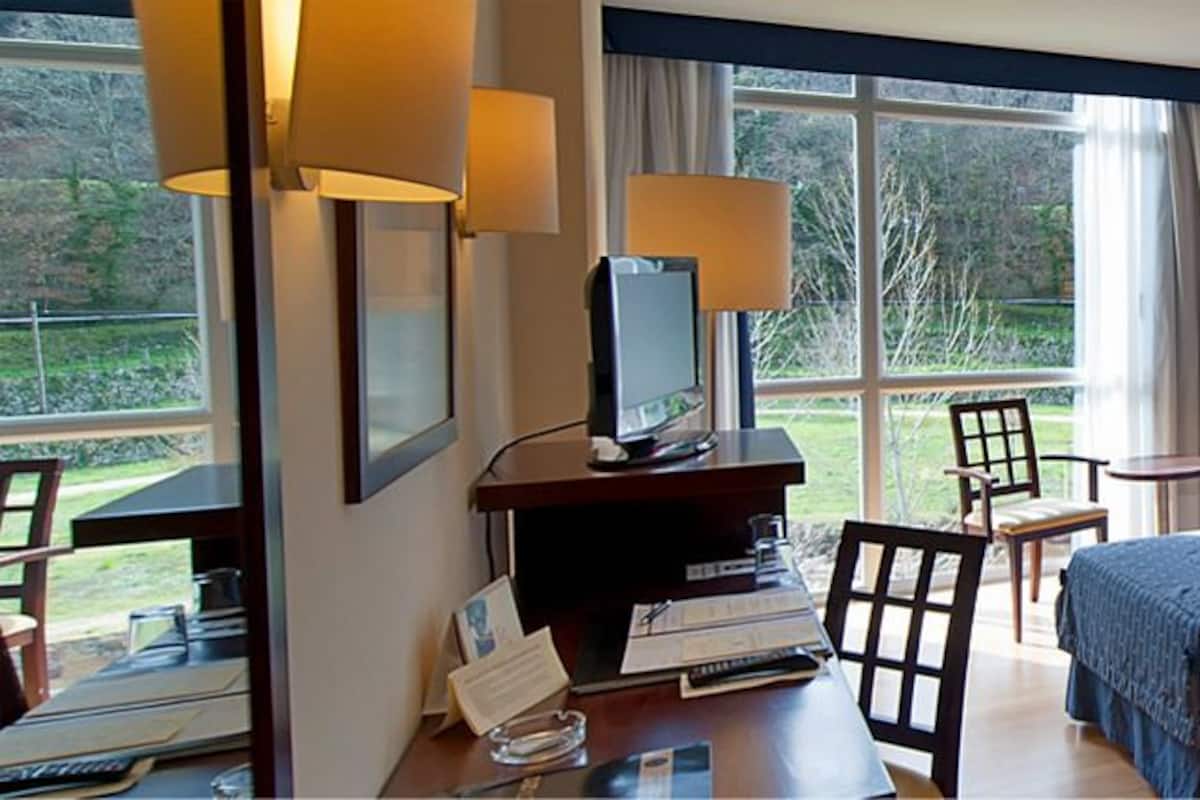 Une chambre d’hôtel avec deux lits, un bureau avec un ordinateur, une chaise et une fenêtre avec des rideaux.