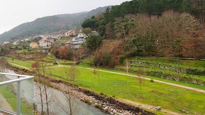 Een balkon met uitzicht op een rivier, een pad en een dorp in de vallei.