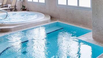 Una piscina interior con jacuzzi y sillones de descanso.